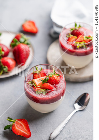 Strawberry and cream panna cotta in glasses with fresh berries on a light background. 114140998