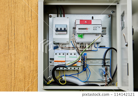 An unlocked wall-mounted outdoor electrical panel with an electricity meter and circuit breakers, as well as three-phase four-core cable prepared for connection to electric distribution board. 114142121