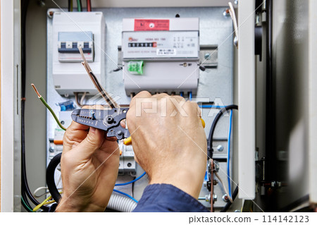 Connecting four-core, three-phase power cable to power supply in an outdoor electrical box, stripping ends of wires of insulation. Connecting four-core, three-phase power cable to power supply in an outdoor electrical box, stripping ends of wires of insulation. 114142123
