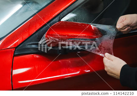 The master applies vinyl film to the side view mirror of a car.  114142210