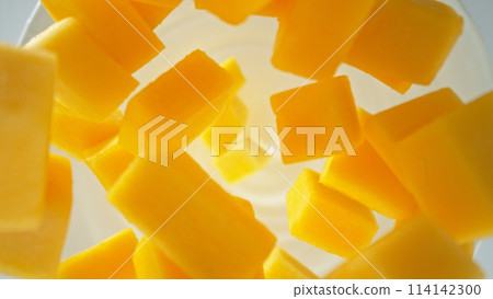 Fresh mango pieces falling into yoghurt cream, top down view 114142300