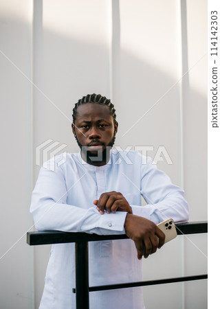 Cheerful male tourist portrait dress in white wear dashiki ethnic smiling at city street or small town background. African American travel model have free time. Millennial generation and gen z people Cheerful male tourist portrait dress in white wear dashiki ethnic smiling at city street or small town background. African American travel model have free time. Millennial generation and gen z people 114142303