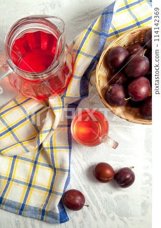 Plum Compote in jug with purple plums on white wooden background. . Plum Compote in jug with purple plums on white wooden background. . 114142369