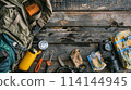 A backpack with a compass and other tools on a wooden table 114144945