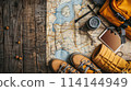 A map is laid out on a wooden table with a backpack and a pair of yellow boots. Concept of adventure and travel 114144949