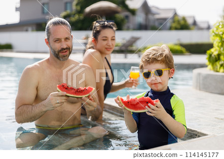 Happy vacation kid boy eat watermelon with family parent have fun enjoy at swimming pool. Happy vacation kid boy eat watermelon with family parent have fun enjoy at swimming pool. 114145177