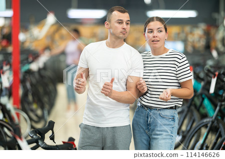 Interested young couple walking through specialized bicycle store 114146626