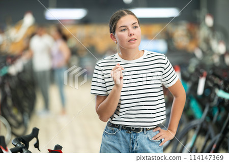 Young woman looking around in bike shop 114147369