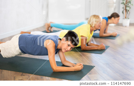 Mother, grandmother and adolescence son do exercise elbow plank pose Sampatasana. 114147690