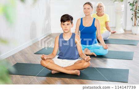 Group of people generation on mats doing yoga exercise lord of fishes pose. 114147739