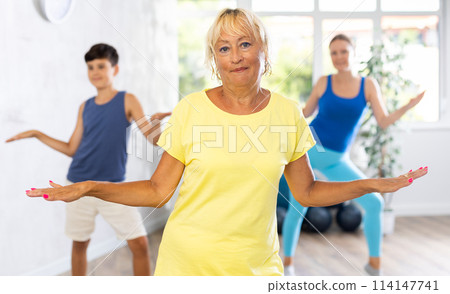 Happy old woman practicing dance positions during workout session Happy old woman practicing dance positions during workout session 114147741