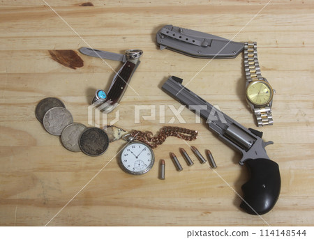Gun With Silver Coins and Pocket Watch on Wooden Table Gun With Silver Coins and Pocket Watch on Wooden Table 114148544