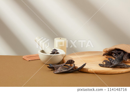 Photo for hair care products, all items including blank wooden tray, locust fruits, mortar and pestle, candle and comb placed on the right side of pic. Space for displaying product, front view Photo for hair care products, all items including blank wooden tray, locust fruits, mortar and pestle, candle and comb placed on the right side of pic. Space for displaying product, front view 114148716