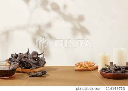 Minimalist hair care lifestyle photo with locust fruit is the main ingredient on brown table from front view. Vacant space for displaying product made from locust Minimalist hair care lifestyle photo with locust fruit is the main ingredient on brown table from front view. Vacant space for displaying product made from locust 114148723