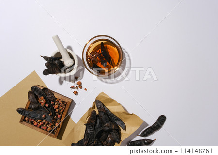 Some black locust fruits and other ingredients featured on bottom left corner, decorated by vintage brown paper. Rustic photo with copy space and high angle view Some black locust fruits and other ingredients featured on bottom left corner, decorated by vintage brown paper. Rustic photo with copy space and high angle view 114148761