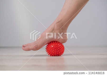 Close-up of a woman's foot on a massage ball with spikes.  114148818