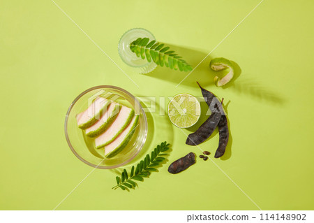 Green background against a group of cosmetic ingredient including black locust pod, lemon, fern and grapefruit peel flat lay. High angle view photography with blank space for adding design elements Green background against a group of cosmetic ingredient including black locust pod, lemon, fern and grapefruit peel flat lay. High angle view photography with blank space for adding design elements 114148902