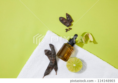 Unlabeled serum bottle placed on white towel beside other ingredients against on green background. Mock up for advertising or branding Unlabeled serum bottle placed on white towel beside other ingredients against on green background. Mock up for advertising or branding 114148903