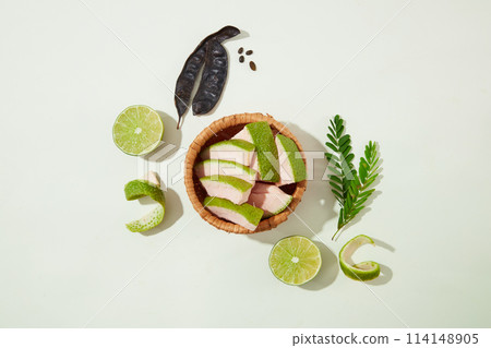 A rattan basket with grapefruit peel contained inside, decorated by lemon, fern and black locust pods. Top view photography for designing advertise of cosmetic product A rattan basket with grapefruit peel contained inside, decorated by lemon, fern and black locust pods. Top view photography for designing advertise of cosmetic product 114148905