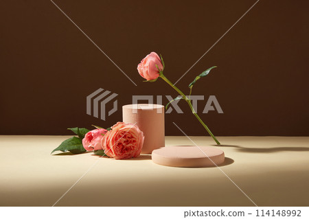 Brown background against on rose theme with empty podium decorated by some branches of rose pink on cream table. Blank space for text and displaying product extract from rose Brown background against on rose theme with empty podium decorated by some branches of rose pink on cream table. Blank space for text and displaying product extract from rose 114148992
