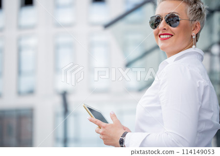 adult Business woman with tablet pc with office district on background adult Business woman with tablet pc with office district on background 114149053