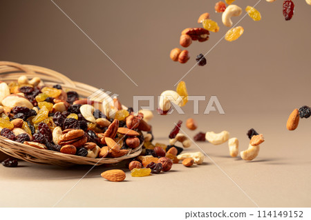 Flying dried fruits and nuts on a beige background. Flying dried fruits and nuts on a beige background. 114149152