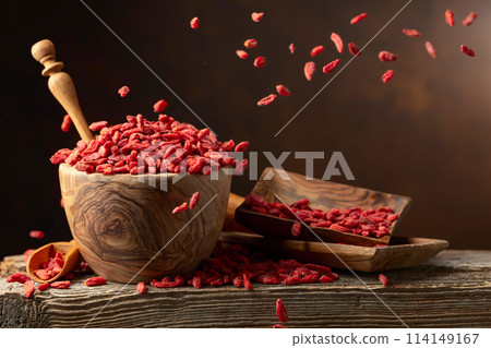 Dried goji berries in wooden bowl on a brown background. Dried goji berries in wooden bowl on a brown background. 114149167