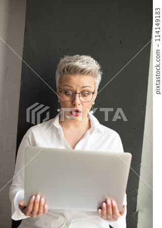 Surprised woman reading unexpected information in laptop with open mouth and bulging eyes Surprised woman reading unexpected information in laptop with open mouth and bulging eyes 114149183