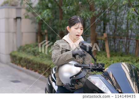 A female biker with a troubled expression A female biker with a troubled expression 114149435