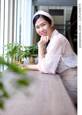 Beautiful Asian businesswoman is smiling and relaxing with smartphone on stool bar in cafe and coffee shop Beautiful Asian businesswoman is smiling and relaxing with smartphone on stool bar in cafe and coffee shop 114149974