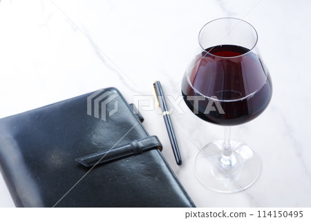 Black leather organizer and a glass of red wine Black leather organizer and a glass of red wine 114150495