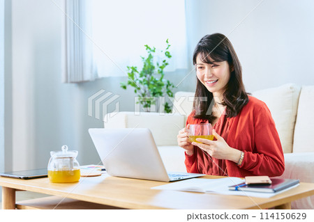 一名女士在休息日在客廳裡用筆記型電腦參加線上課程,以重新學習和重新掌握技能。 一名女士在休息日在客廳裡用筆記型電腦參加線上課程,以重新學習和重新掌握技能。 114150629