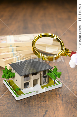 A miniature house and a stack of bills (+magnifying glass) 114150704