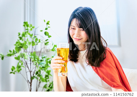 一名 30 多歲的女性看著一瓶啤酒,手裡拿著它,想獨自喝午餐,以緩解假期明媚一天的壓力。 一名 30 多歲的女性看著一瓶啤酒,手裡拿著它,想獨自喝午餐,以緩解假期明媚一天的壓力。 114150762