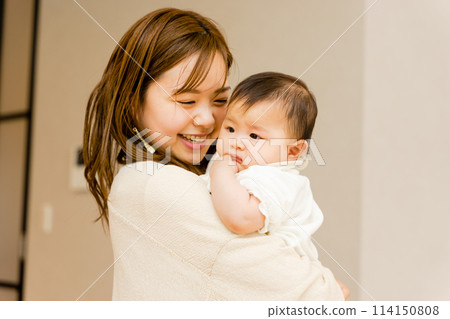 Happy mother holding her baby indoors 114150808