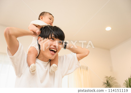 A smiling father in his 20s or 30s having fun carrying his 0-year-old baby on his shoulders 114151119