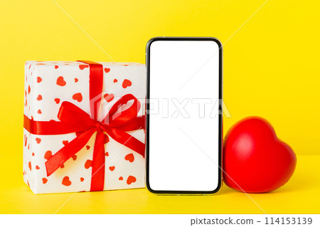mobile phone with blank screen on colored background with hearts, calendar and gift box, valentine day concept perspertive view flat lay mobile phone with blank screen on colored background with hearts, calendar and gift box, valentine day concept perspertive view flat lay 114153139