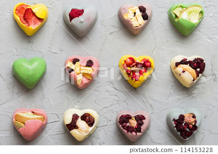 chocolate sweets in the form of a heart with fruits and nuts on a colored background. top view with space for text, holiday concept 114153228