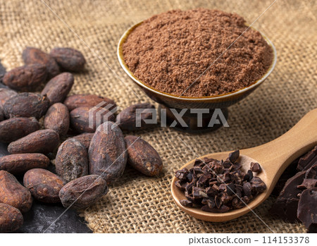 Cocoa beans and cocoa pod on a wooden surface. Cocoa beans and cocoa pod on a wooden surface. 114153378