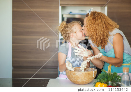 Mother and child daughter girl having fun while making dinner at the kitchen. 114153442