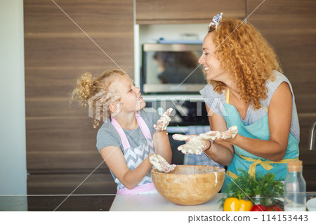 Mother and child daughter girl having fun while making dinner at the kitchen. 114153443