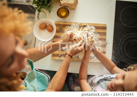 Top view of woman and little daughter making cookies while cooking on kitchen. 114153445