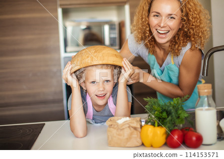 Mother and daughter having fun in the kitchen while preparing cookies. Mother and daughter having fun in the kitchen while preparing cookies. 114153571