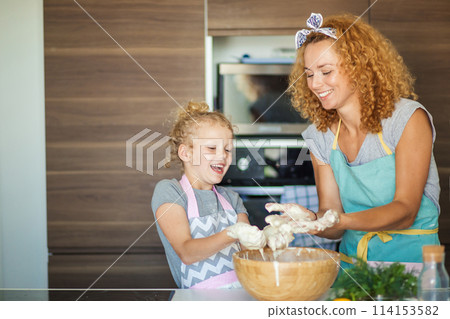 Mother and child daughter girl having fun while making dinner at the kitchen. 114153582