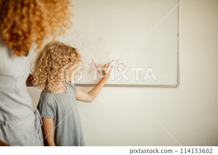 Little girl with mom writing on board with marker. Learning and school concept. Little girl with mom writing on board with marker. Learning and school concept. 114153682