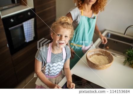 Attractive young woman and her little cute daughter are cooking at kitchen. Attractive young woman and her little cute daughter are cooking at kitchen. 114153684