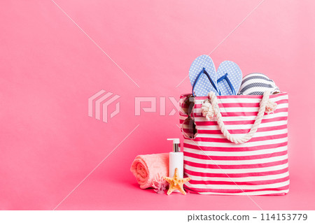 Stylish bag with beach accessories . Summer holiday concept. Top view of beach bag with sunscreen cream with space for text Stylish bag with beach accessories . Summer holiday concept. Top view of beach bag with sunscreen cream with space for text 114153779
