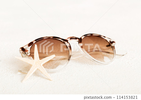 sunglasses with seashell lying on table background. Sunglasses on summer background. Top view flat lay with copy space for text 114153821