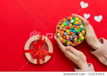 Female hands with delicious candies in box on color background Female hands with delicious candies in box on color background 114153919