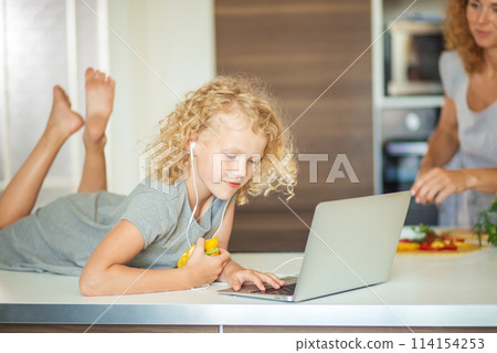 Little girl and her daughter baking cookies at home, reading recipe on laptop. Little girl and her daughter baking cookies at home, reading recipe on laptop. 114154253